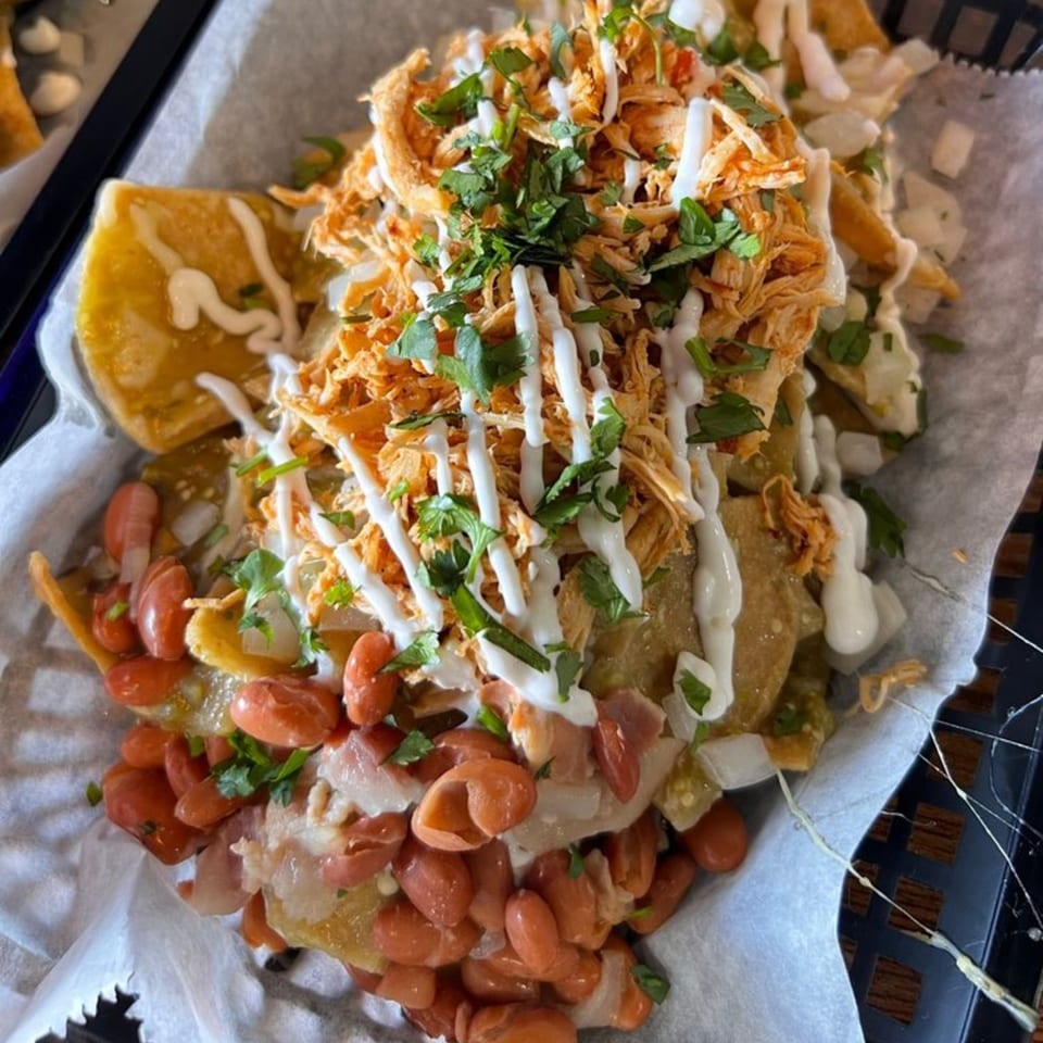 Al Chile Taco Bar's chilaquiles with shredded chicken, pinto beans, cilantro, and crema.